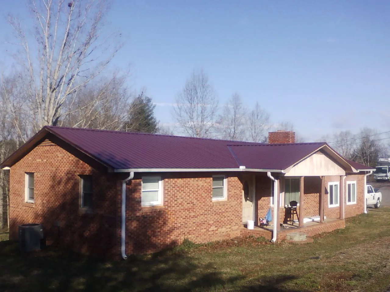 Burgundy metal roof on a brick ranch home with a new addition in Nashua