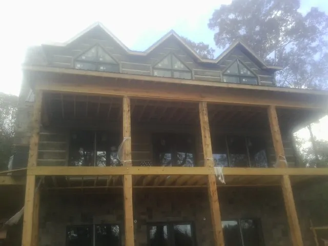 Dormers and porch framing on a large log home under construction — Roof Coating work by our crew in Nashua