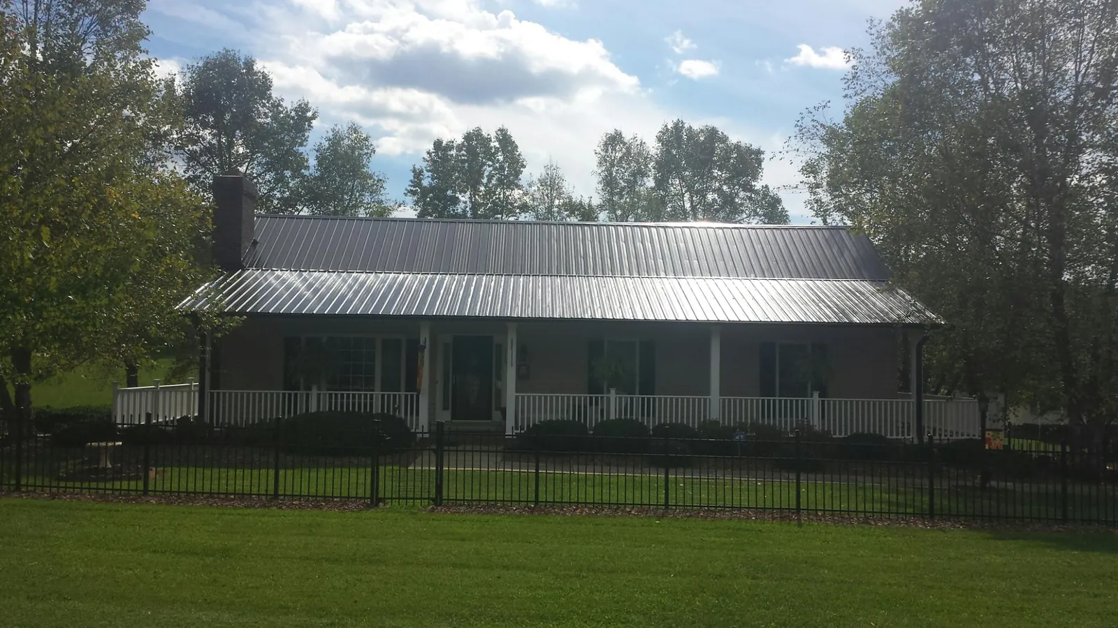 Gray metal roof on a brick ranch with a full width front porch — Gutter Guard Installation work by our crew in Nashua