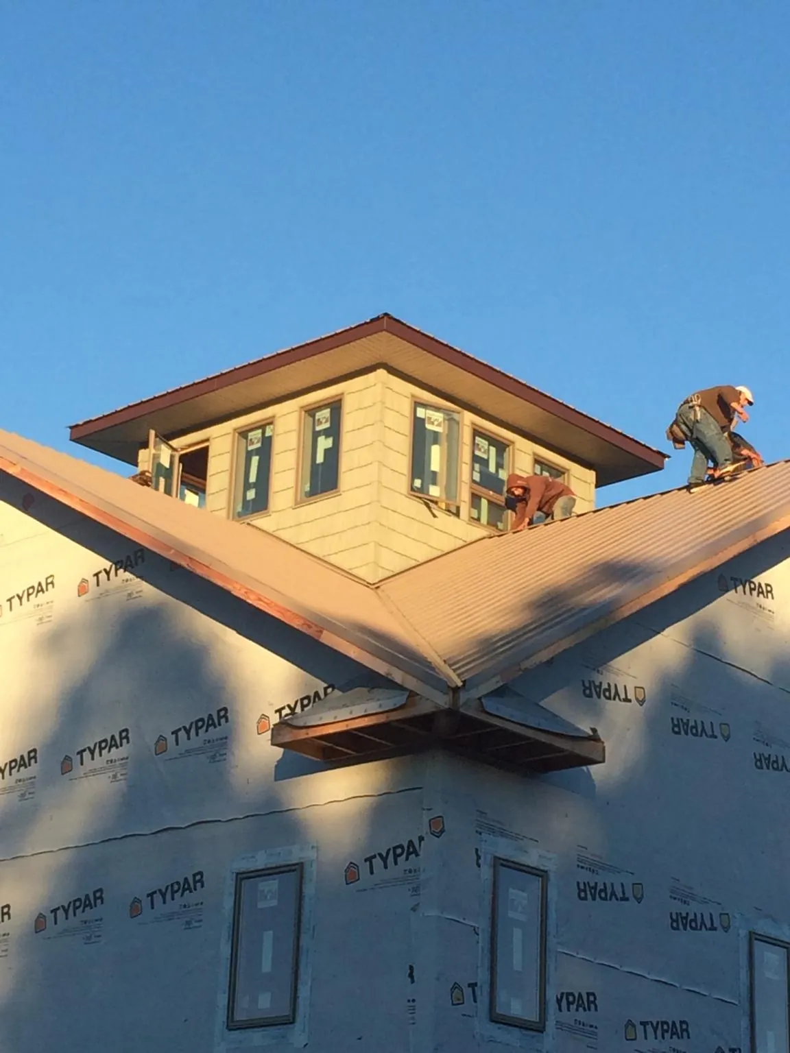 Roofers working around a rooftop cupola on a new metal roof at sunset — Roof Waterproofing in Nashua by Roofing Brothers